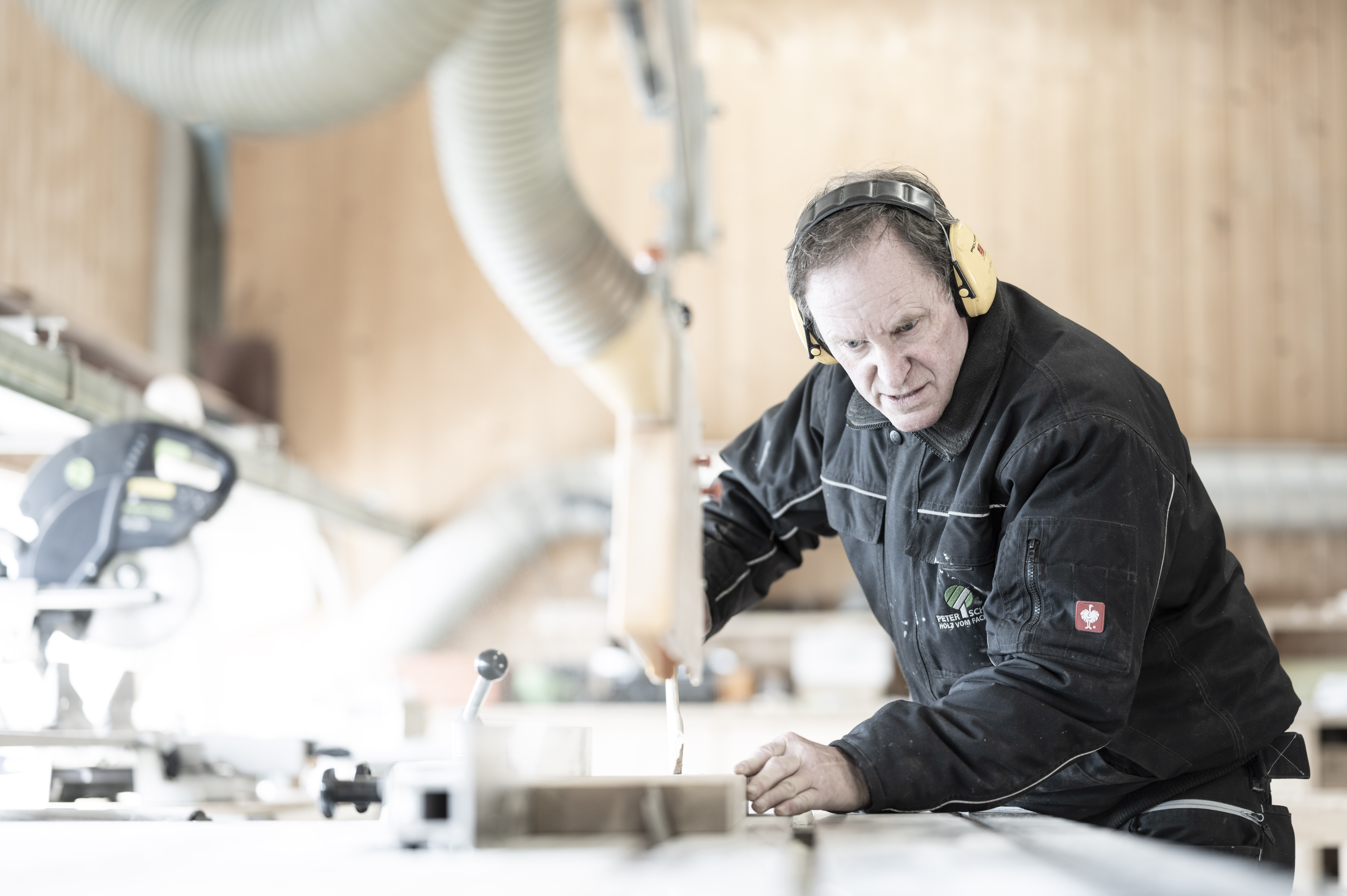 Mitarbeiter schneidet Platte an Kreissäge zu